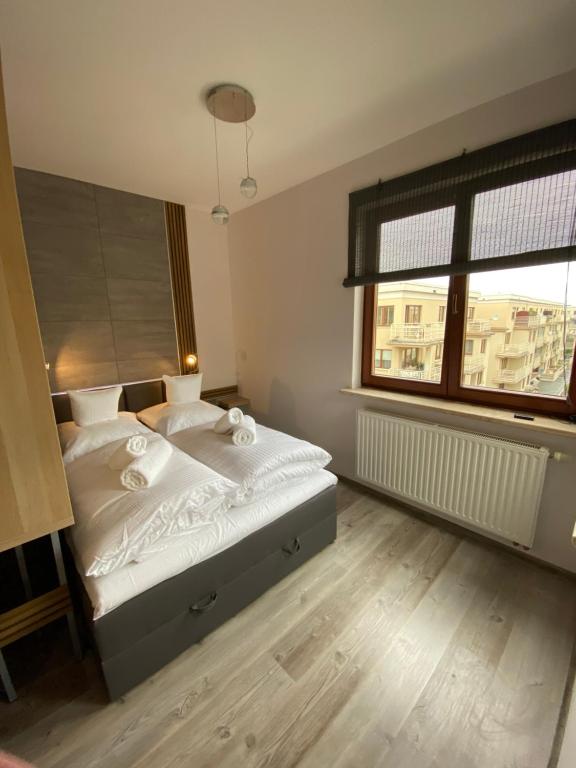 a bedroom with a bed with white sheets and a window at Apartament Drewno i Morze in Gdańsk