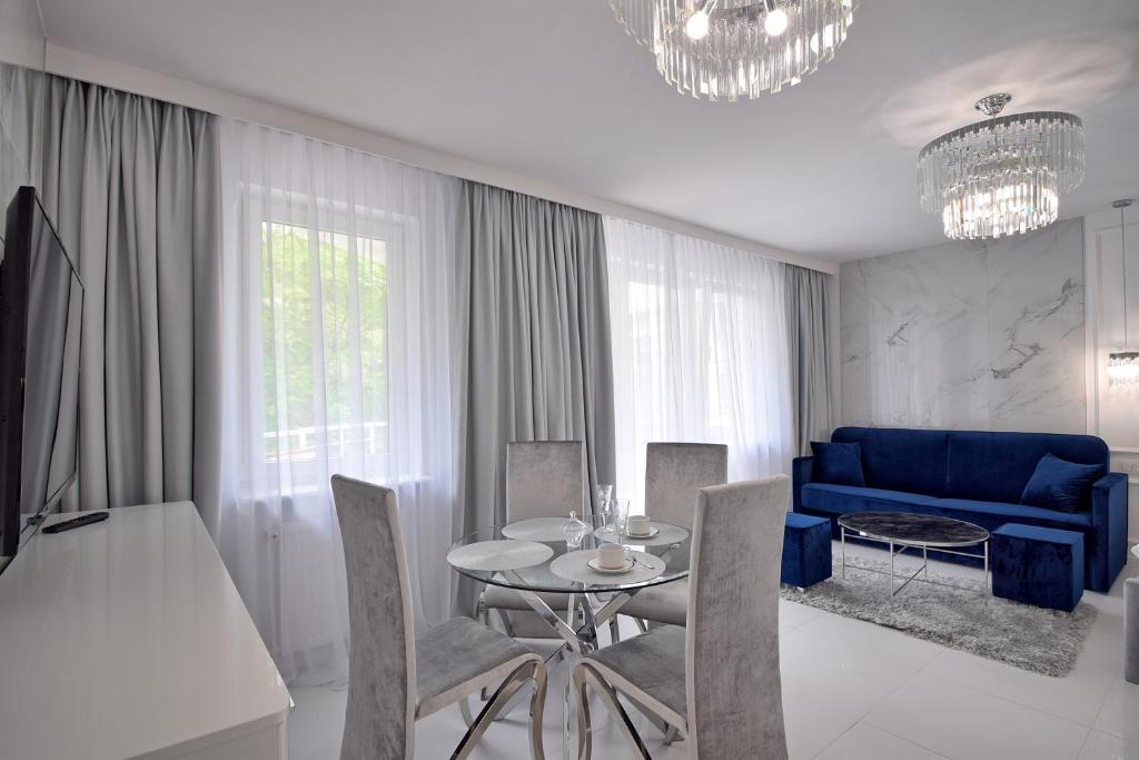 salon ze stołem i niebieską kanapą w obiekcie CRYSTAL Apartament 80m od plaży w Kołobrzegu