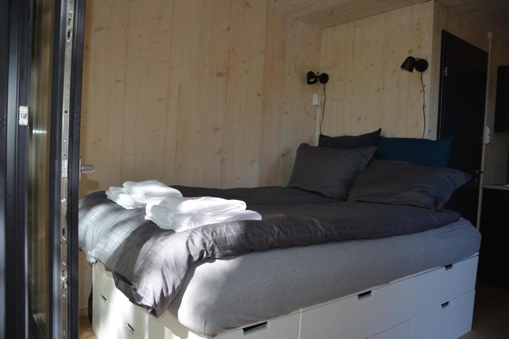 a large bed in a room with wooden walls at Treehut, nature, birds, silence and fjord in Samlanes
