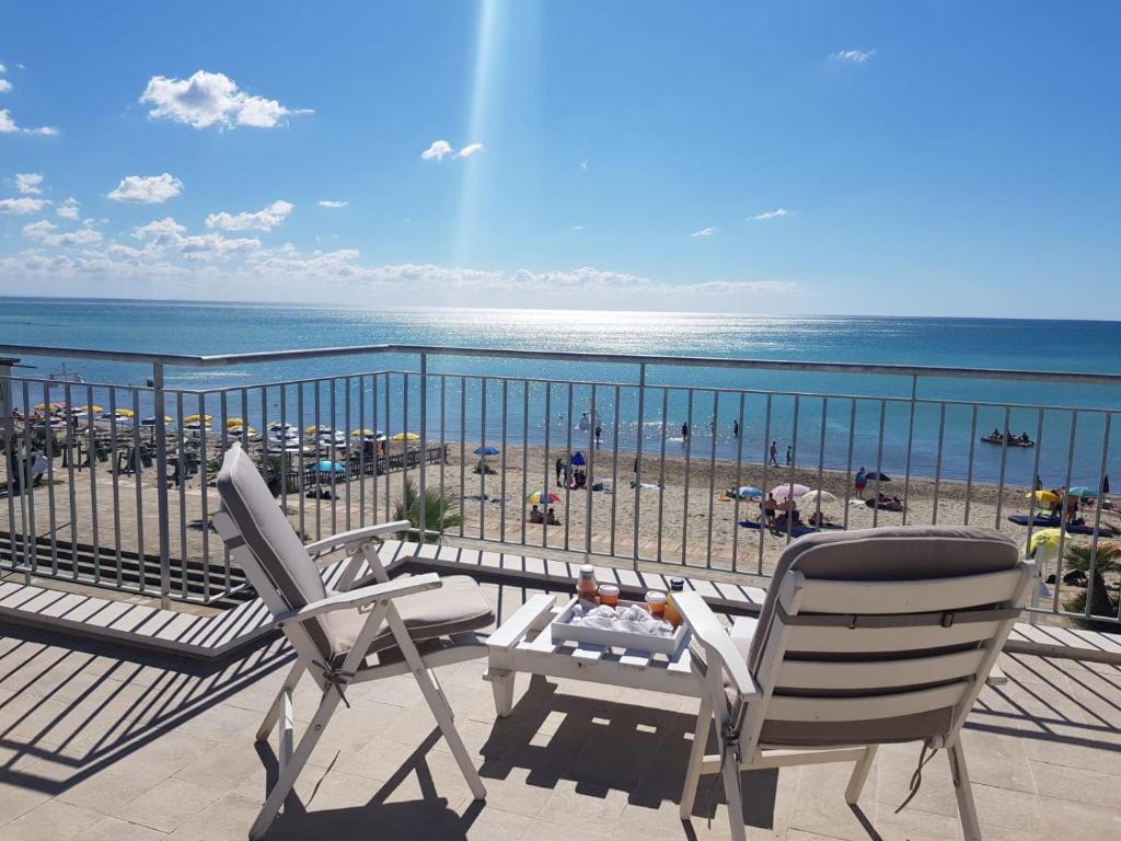 einen Balkon mit 2 Stühlen, einem Tisch und dem Strand in der Unterkunft Iris home in Metaponto