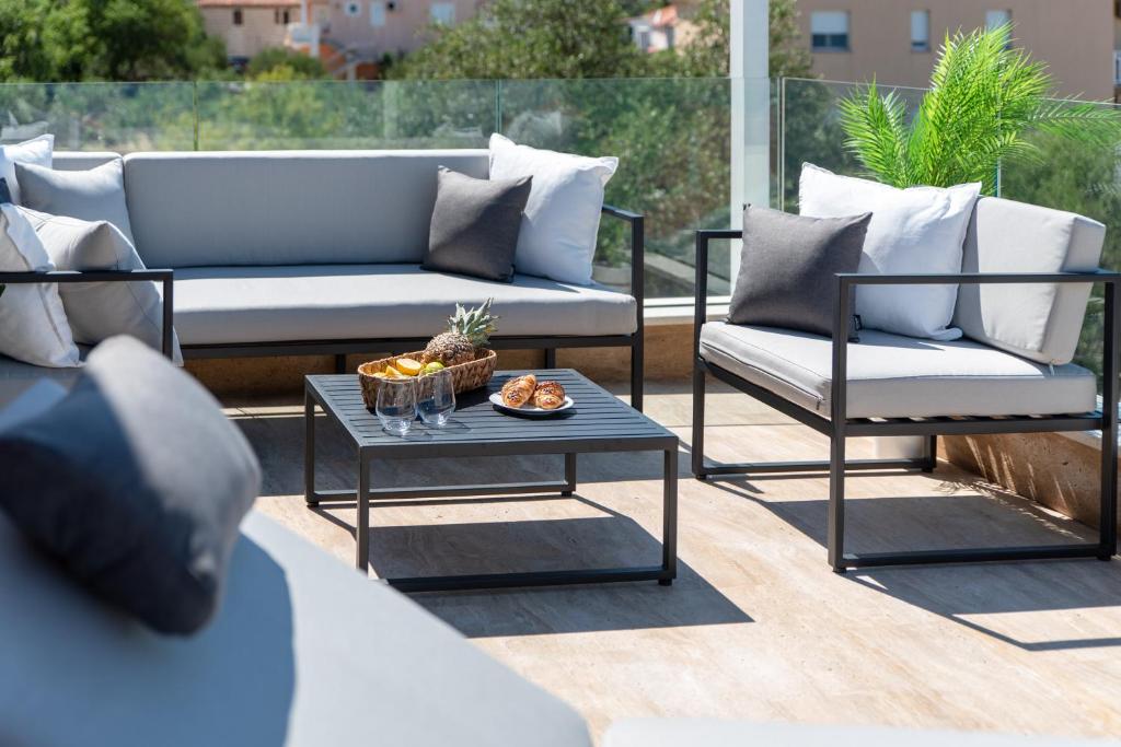 eine Terrasse mit einem Sofa, 2 Stühlen und einem Tisch in der Unterkunft Apartments Belmat in Trogir