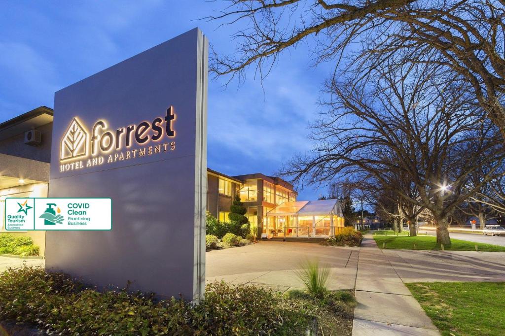 una señal frente a un edificio con una casa en Forrest Hotel & Apartments, en Canberra