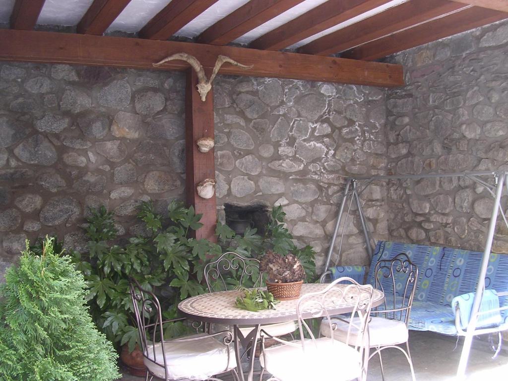 un patio con mesa, sillas y pared de piedra. en Casa Torres, en San Juan de Plan