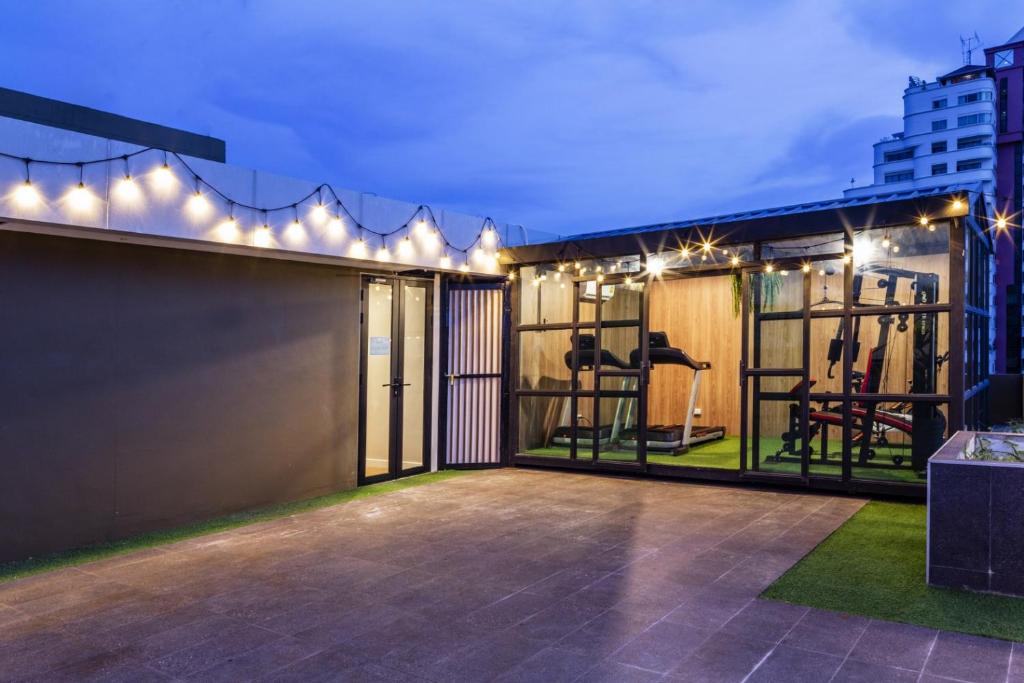 A rooftop exercise area with cardio and strength equipment under string lights.