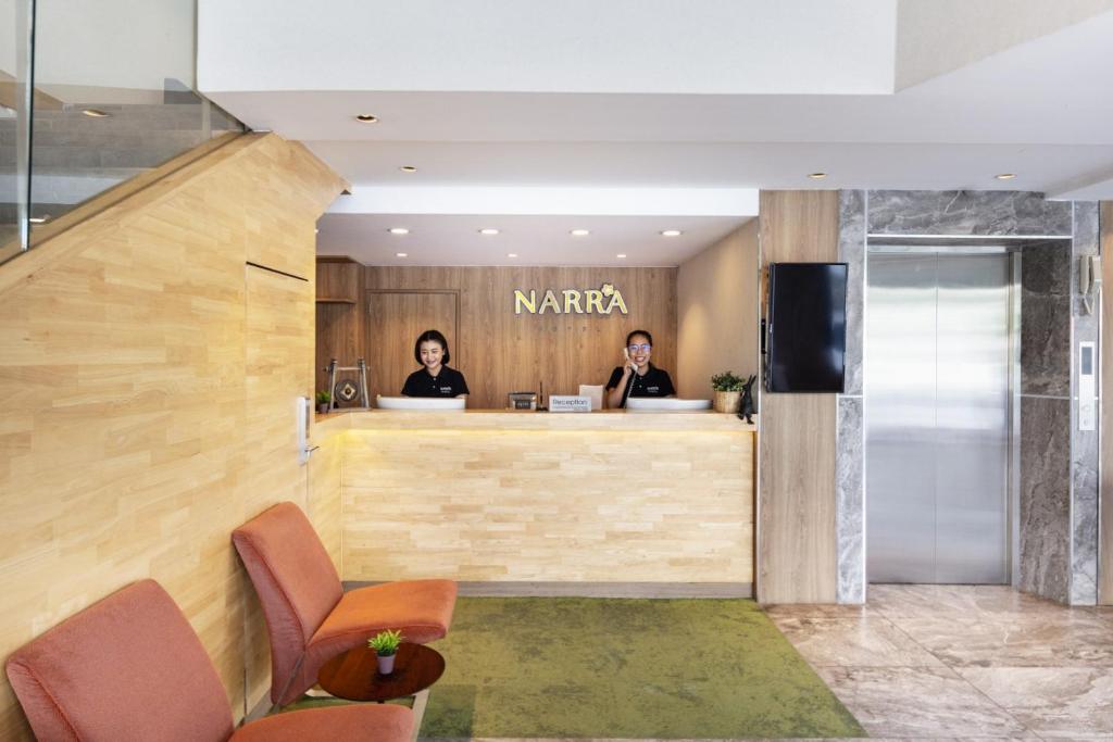 A compact reception lobby has a wood-front desk, two attendants and an elevator beside it.