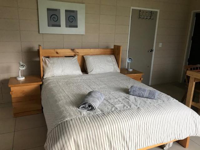 a bedroom with a large bed with two pillows at Room with a view in Waipu