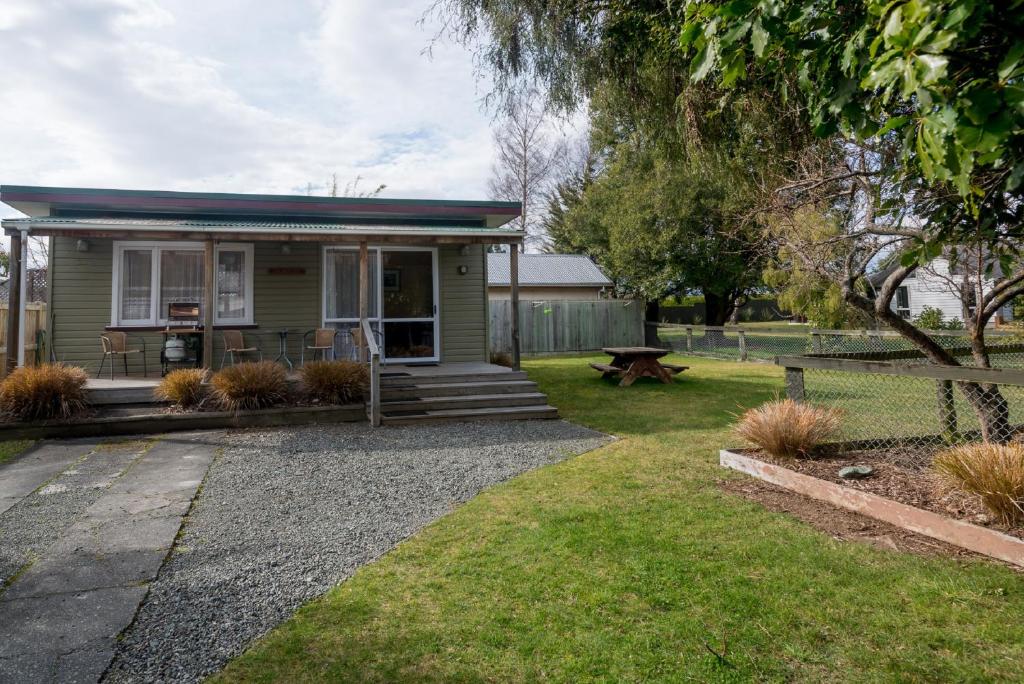 una piccola casa verde con un tavolo da picnic nel cortile di Accommodation Fiordland The Bach - One Bedroom Cottage at 226B Milford Road a Te Anau