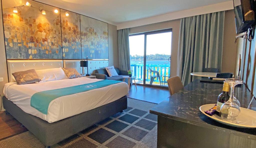 a hotel room with a large bed and a large window at Mariners on the Waterfront in Batemans Bay