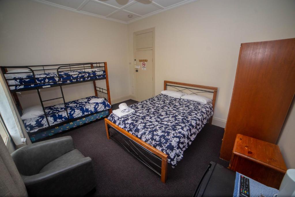 a small bedroom with two bunk beds and a chair at Australian Hotel in Ballina