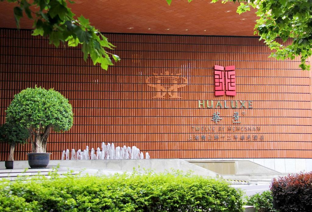 HUALUXE Shanghai Twelve At Hengshan, an IHG Hotel في شانغهاي: مبنى امامه نافورة ماء