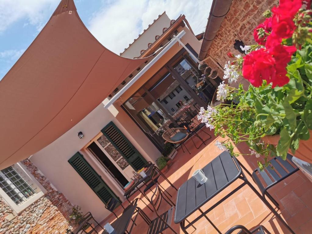 ein Gebäude mit Tischen, Stühlen und roten Blumen in der Unterkunft L'Iris B&B in Terrazza in Lucca