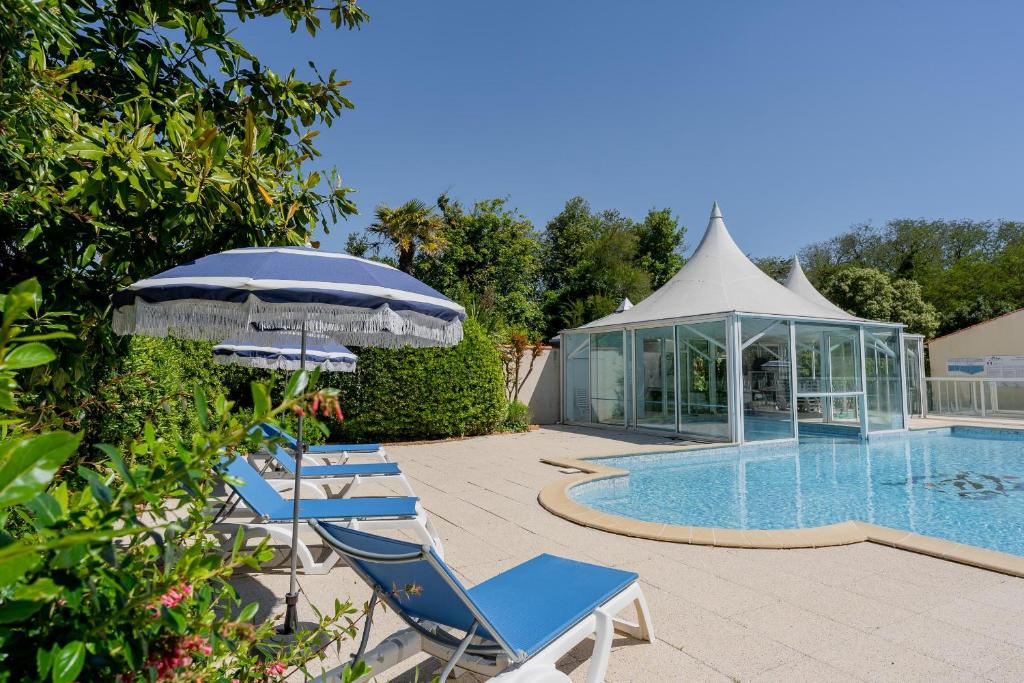 a couple of chairs and an umbrella next to a swimming pool at L'Ocean in Saint-Vincent-sur-Jard