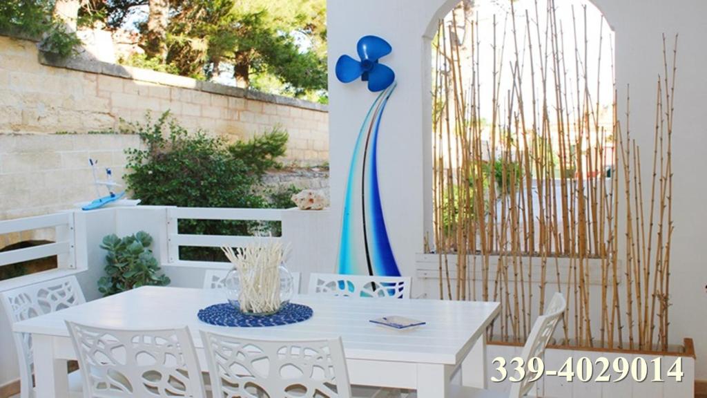 een witte tafel en stoelen op een patio met een hek bij Leuca Casa del Mare in centro in Leuca