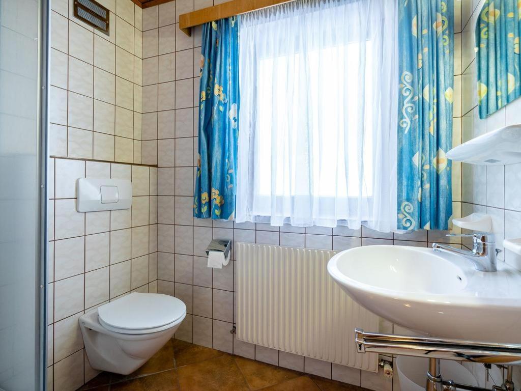 łazienka z umywalką, toaletą i oknem w obiekcie Appartements Maurer w mieście Flachau