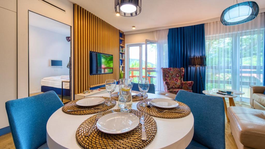 une salle à manger avec une table blanche et des chaises bleues dans l'établissement Apartament 41 Holiday Mountain Residence - 5D Apartamenty, à Świeradów-Zdrój