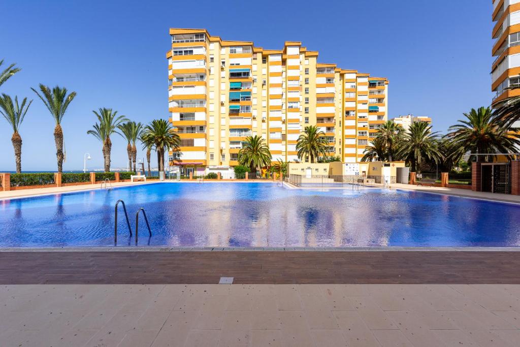 a large swimming pool in front of a building at Apartamento primera linea playa Algarrobo Costa in Algarrobo-Costa