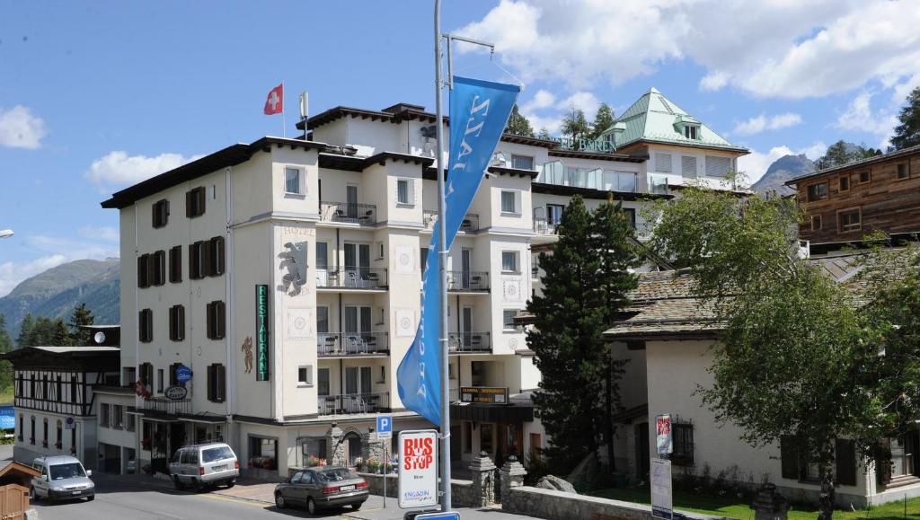 a white building with blue flags in front of it at Hotel Bären in St. Moritz