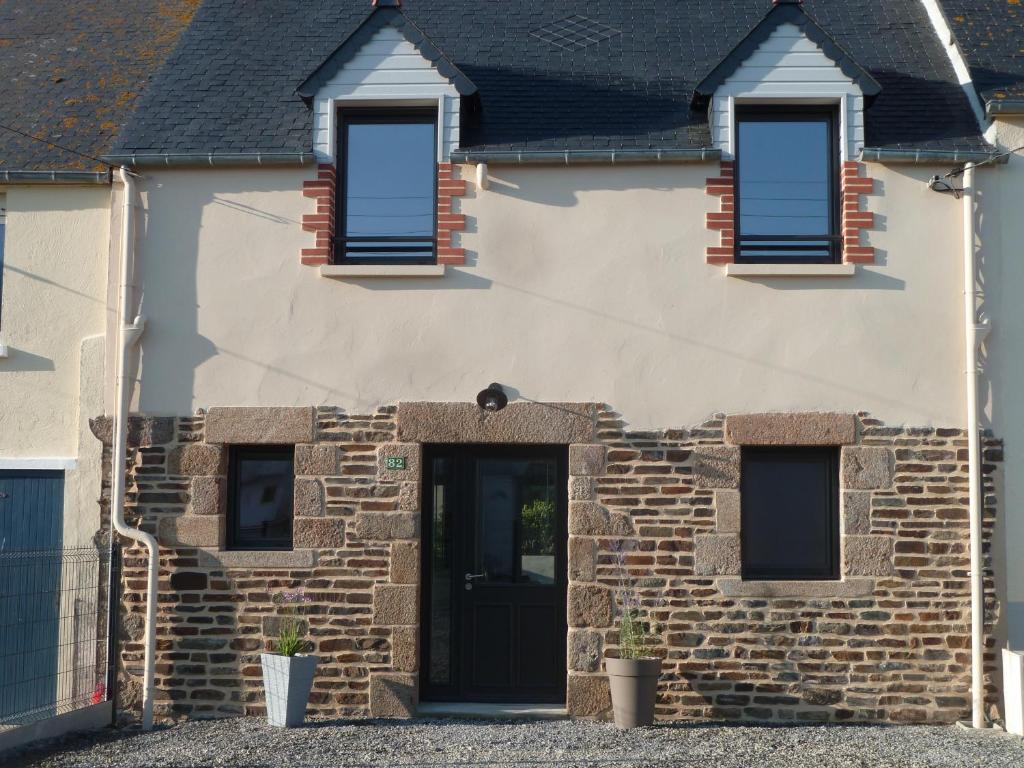 una casa de ladrillo con una puerta y ventanas negras en Chez charlotte, en Cherrueix