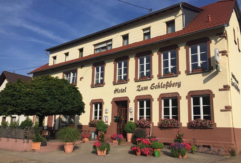 a building with flowers in pots in front of it at Hotel Restaurant zum Schlossberg in Wadern