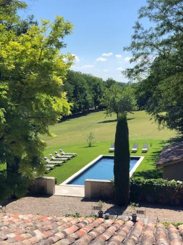 a swimming pool in a yard with chairs and a tree at La Ferme de Gringalet in Anthon