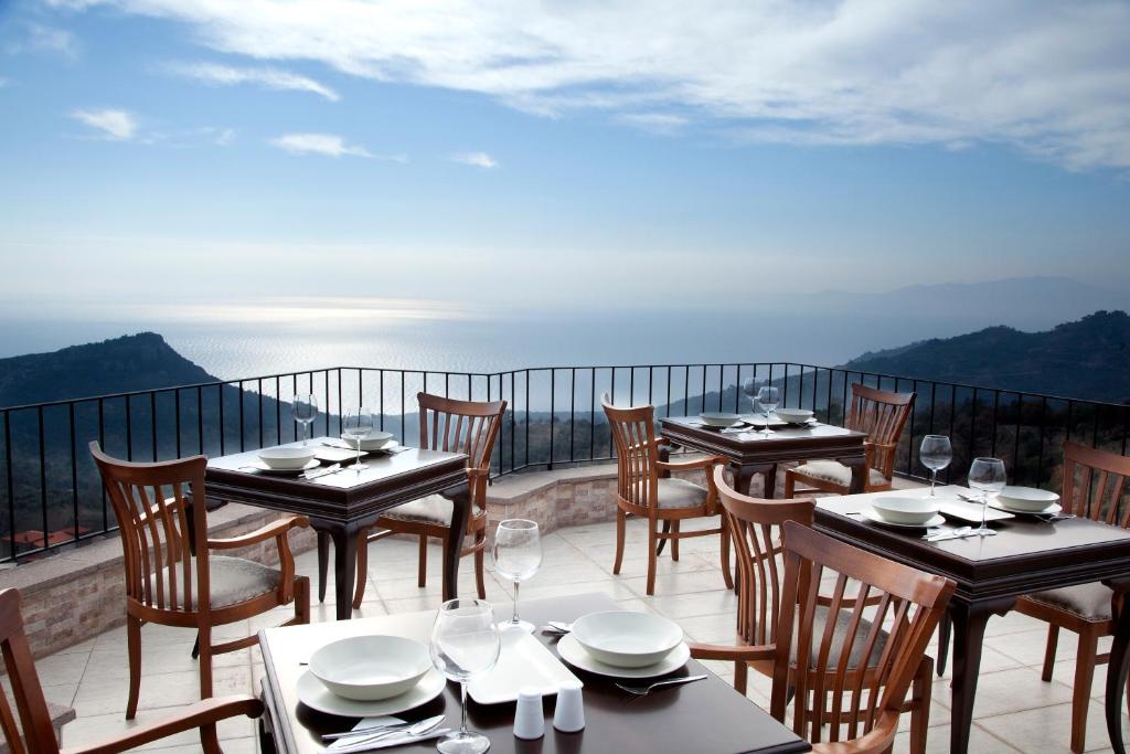 restauracja ze stołami i krzesłami na balkonie w obiekcie Assos Kayalar Terrace w mieście Sazlı