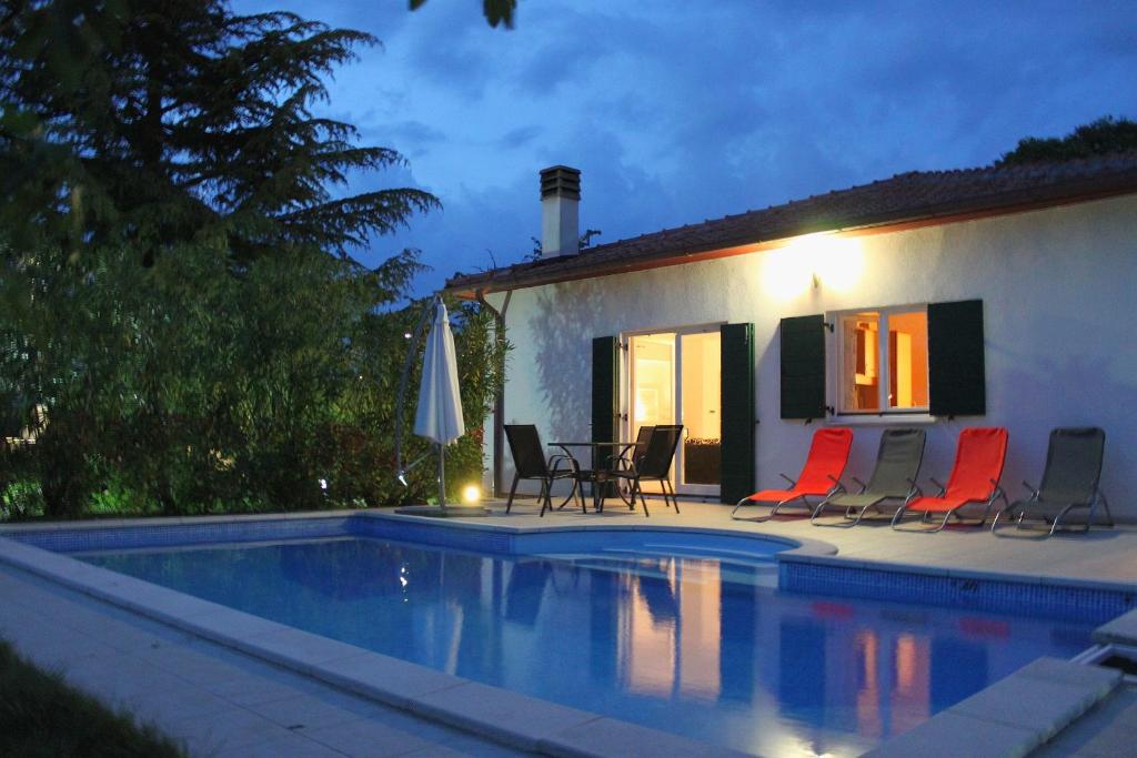 a house with a swimming pool with chairs and an umbrella at Villa Dva Pina in Kanfanar