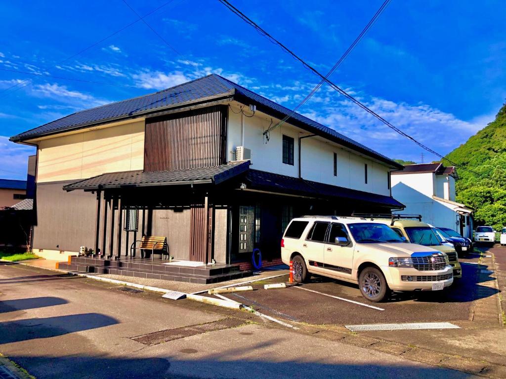 a white suv parked in a parking lot in front of a building at Ricco Mond Hills Apartment Houseアパートタイプの宿は宿泊者と接しない 安全な宿 in Nachikatsuura
