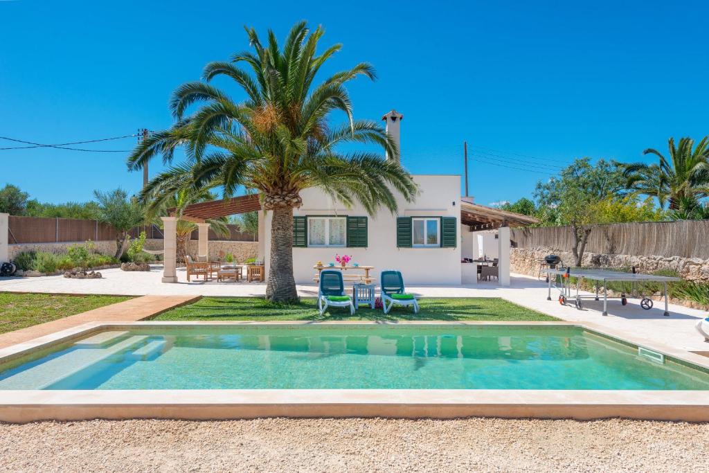 a swimming pool in front of a house with a palm tree at Las Estrellas in Cala Llombards