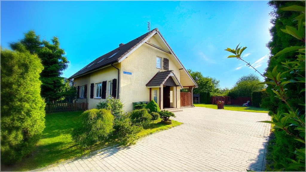 a small white house with a driveway at Dom murowany Siedlisko in Sarbinowo