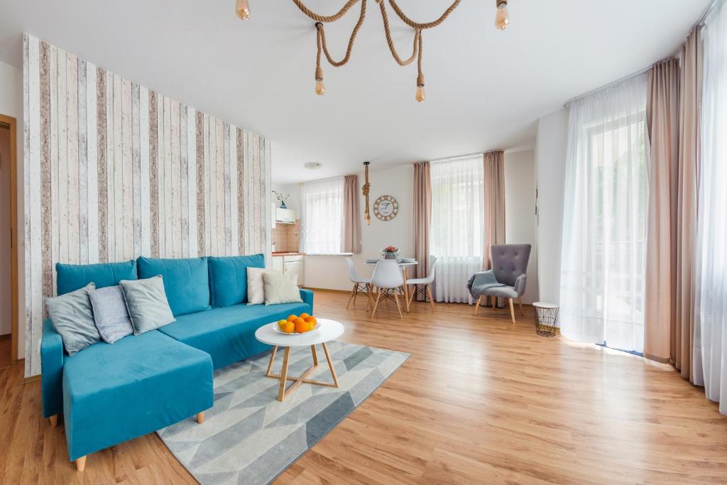a living room with a blue couch and a table at Apartamenty Sun & Snow Olymp in Kołobrzeg
