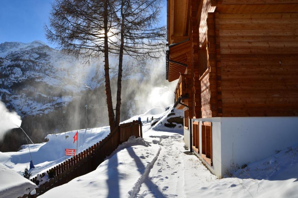 a house in the snow next to a mountain at Apartments Les Marmottes in Zermatt