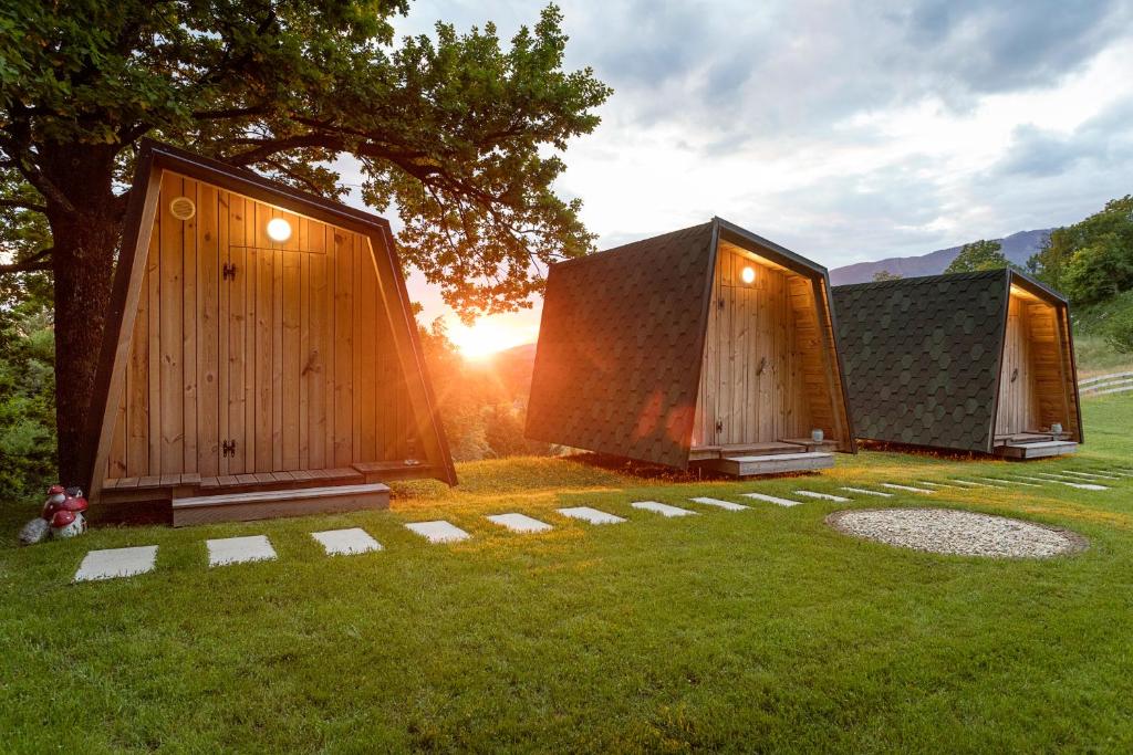 drei winzige Häuser im Gras mit Sonnenuntergang in der Unterkunft Glamping Health Resort in Kamnik