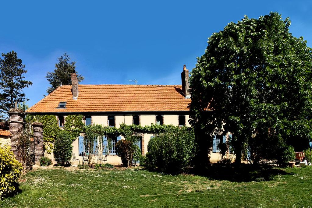 ein Haus mit einem roten Dach und einem Baum in der Unterkunft Le clos des artistes - Chambres d'hôtes in Turny