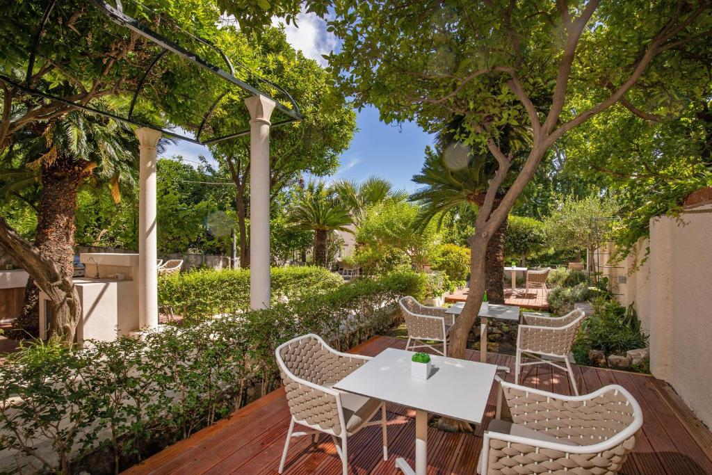 a patio with tables and chairs under trees at Heritage Villa Nobile in Dubrovnik