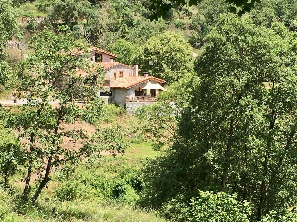 ein Haus inmitten eines Feldes mit Bäumen in der Unterkunft Can Poca Roba in Sant Pere de Torelló