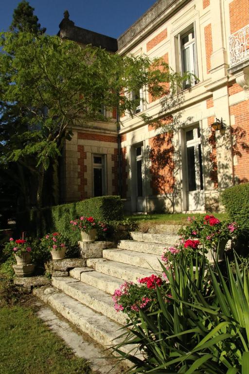um caminho de pedra que leva a uma casa com flores em Domaine de Champ rose em Saint-Laurent-de-Belzagot