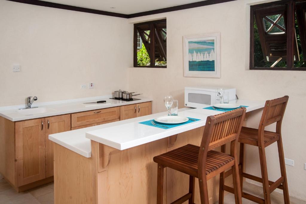 a kitchen with a counter with two chairs and a microwave at Santosha Barbados in Saint Andrew