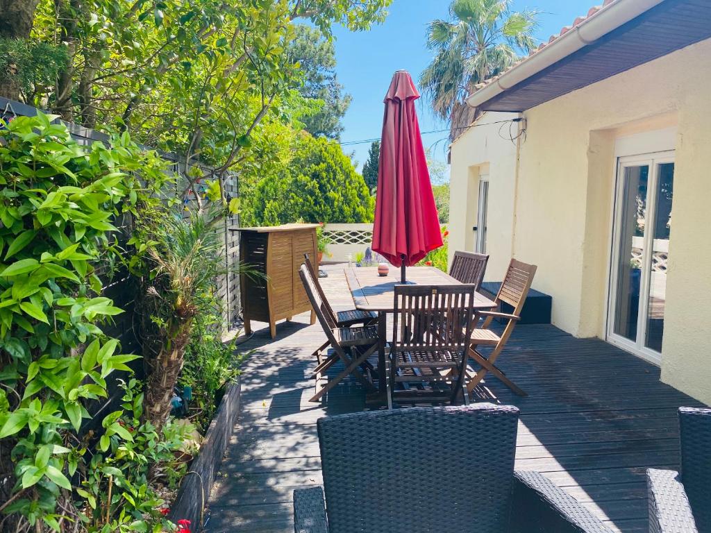 un patio con mesa, sombrilla roja y sillas en Appartement La Perle Noire, en Agde