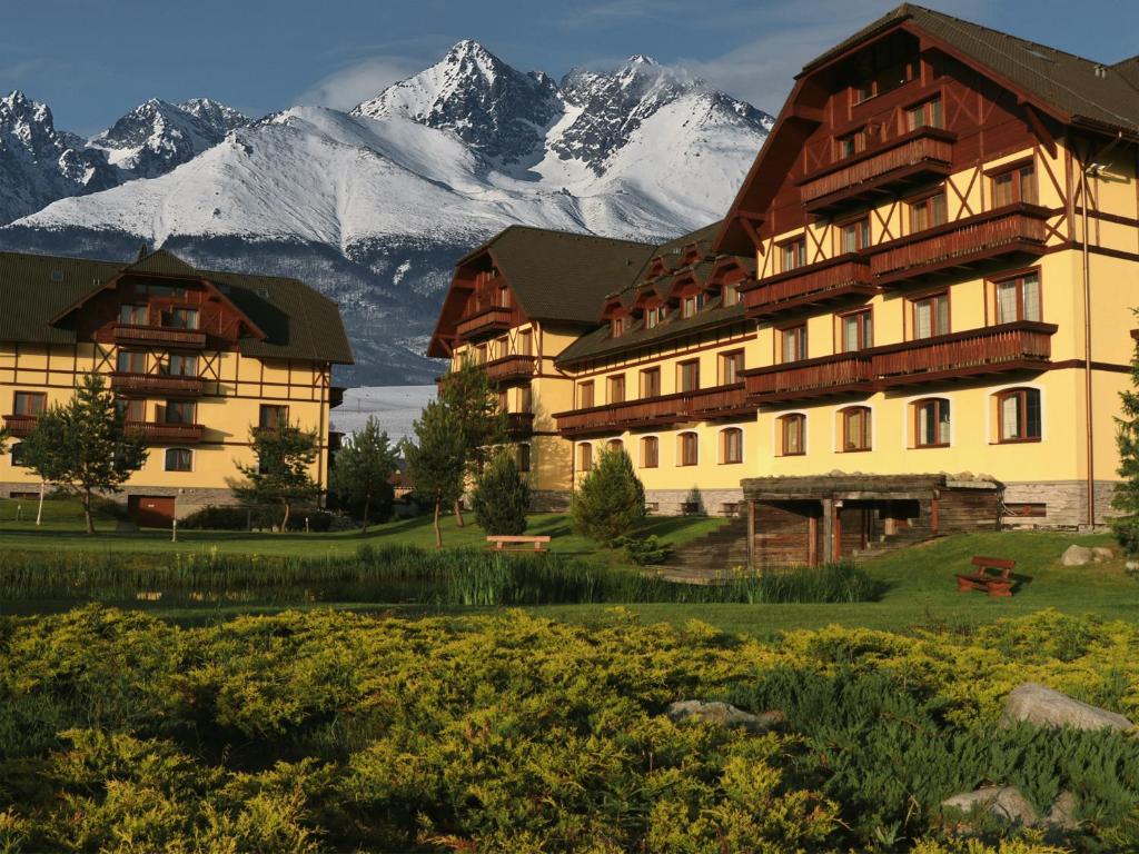 a large building with snow covered mountains in the background at Apartmán Vysoké Tatry Lomnica A4/2 in Veľká Lomnica