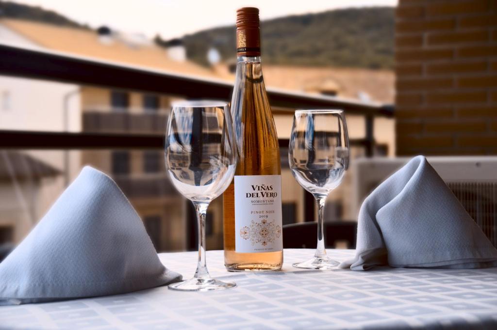 una botella de vino sentada en una mesa con dos copas en AP Guest House Ainsa Pirineos en Aínsa
