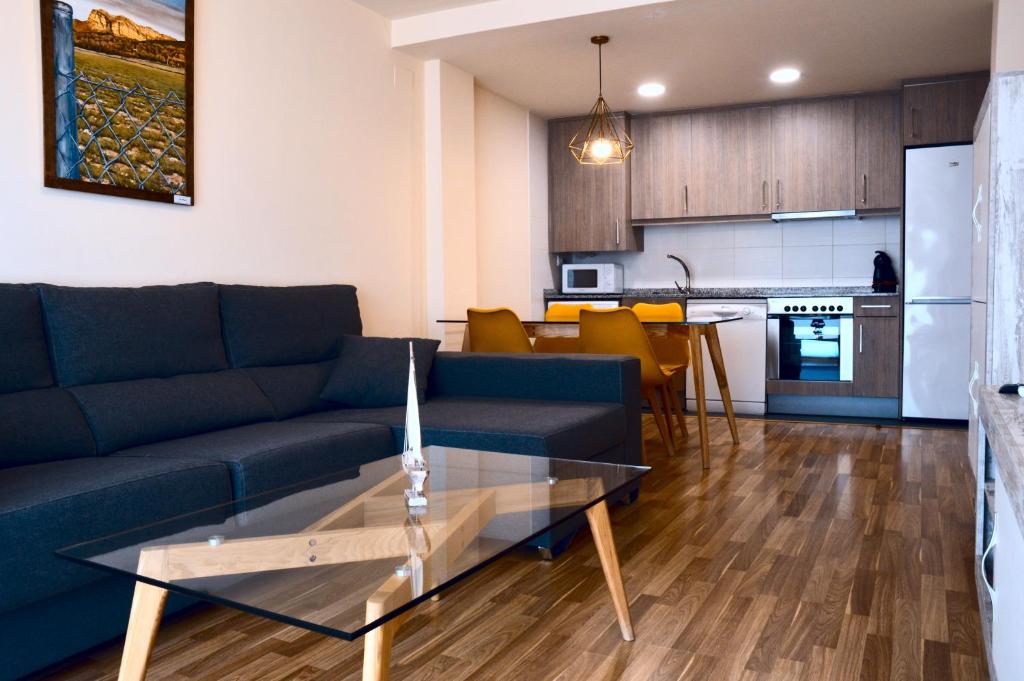 AP Guest House Ainsa Pirineos في أينسا: غرفة معيشة مع أريكة زرقاء وطاولة زجاجية