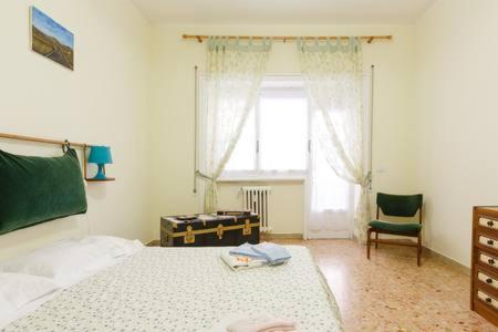 sypialnia z łóżkiem, krzesłem i oknem w obiekcie Bea Home sarai il benvenuto! w Rzymie