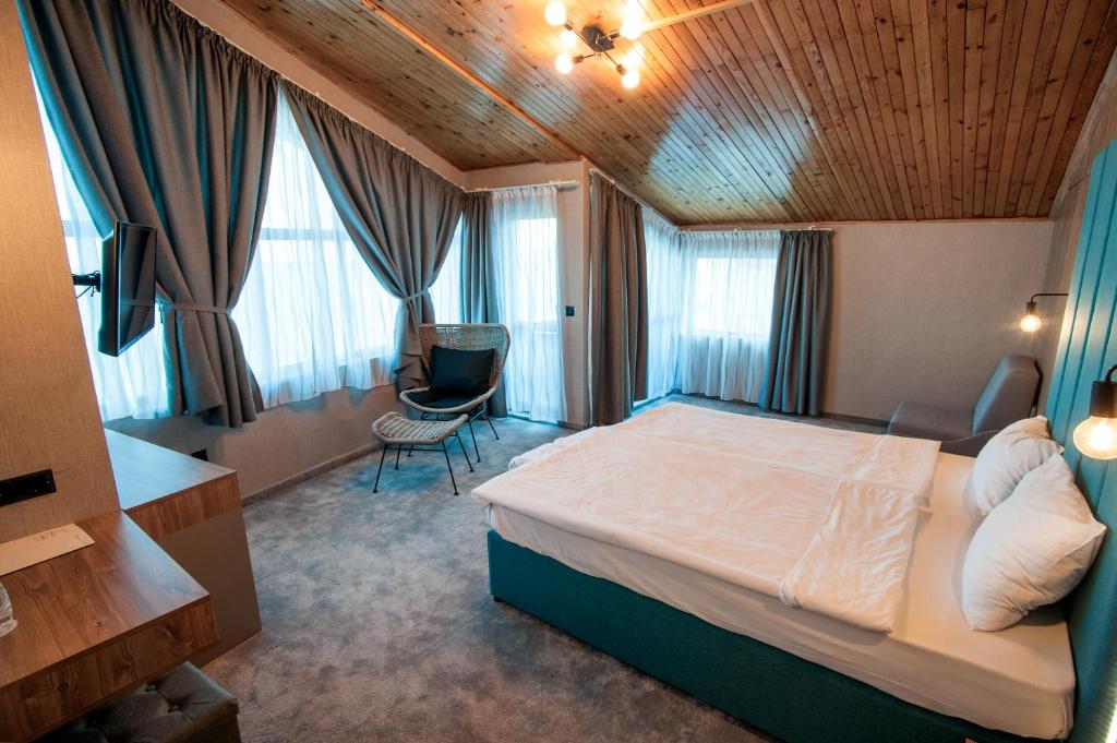sypialnia z łóżkiem, krzesłem i oknami w obiekcie White House Family Hotel Spa zone w Bałcziku