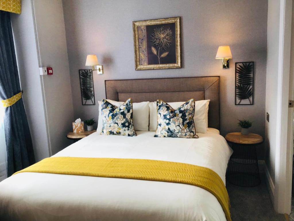 a bedroom with a large bed with yellow and blue pillows at The Alexander in Scarborough