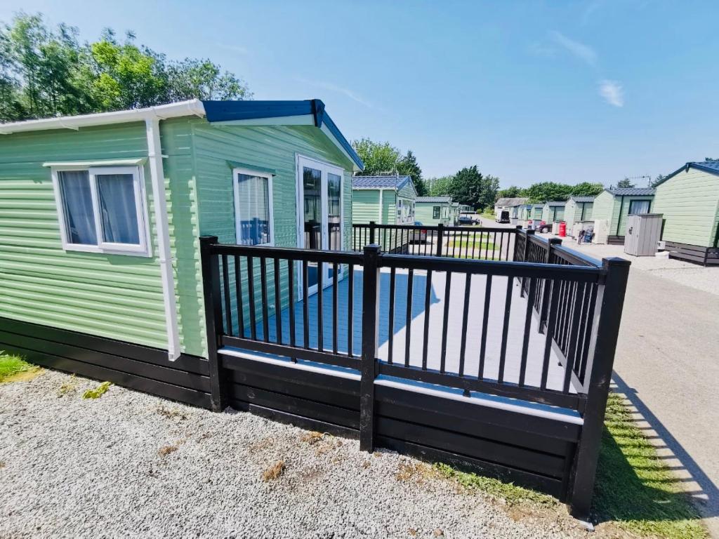 a green tiny house with a black fence at 12 Borwick Lakes by Waterside Holiday Lodges in Carnforth