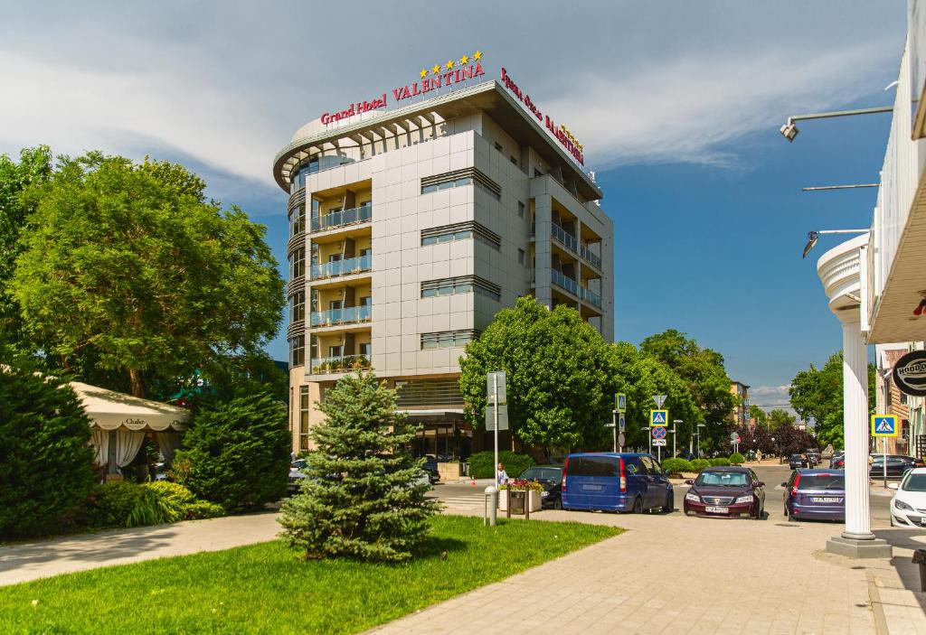 a hotel building with cars parked in a parking lot at Grand Hotel Valentina in Anapa