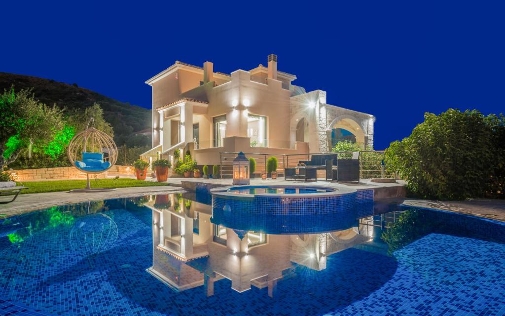 duży dom z basenem przed nim w obiekcie Romanza Luxury Villa w Kalamákion