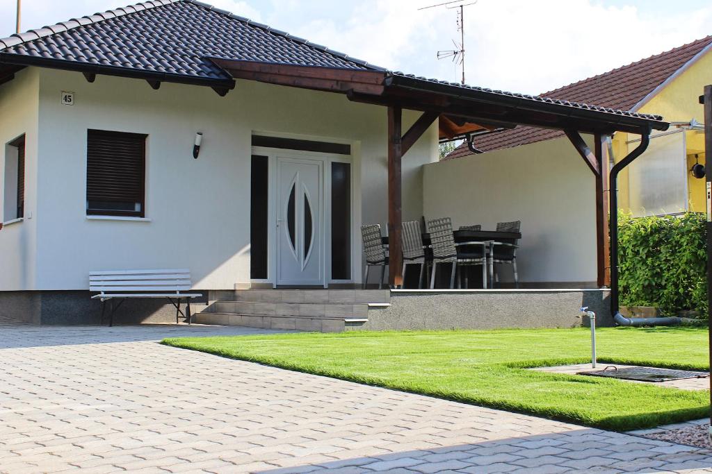 Casa con porche con banco y césped en Tisza Dream Apartman en Tiszakécske