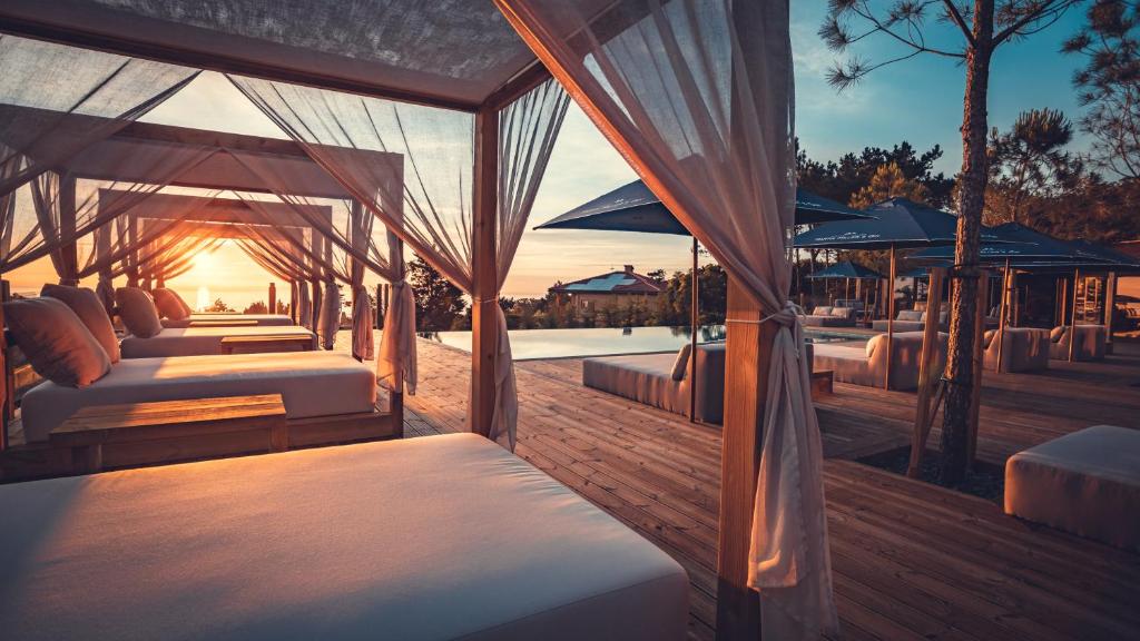 a row of beds on a deck with the sun setting at Charm Nature in Azoia