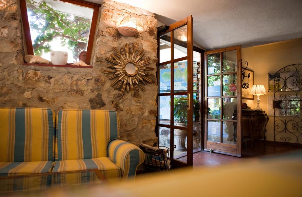 a living room with two chairs and a stone wall at Hotel Danila in Portoferraio